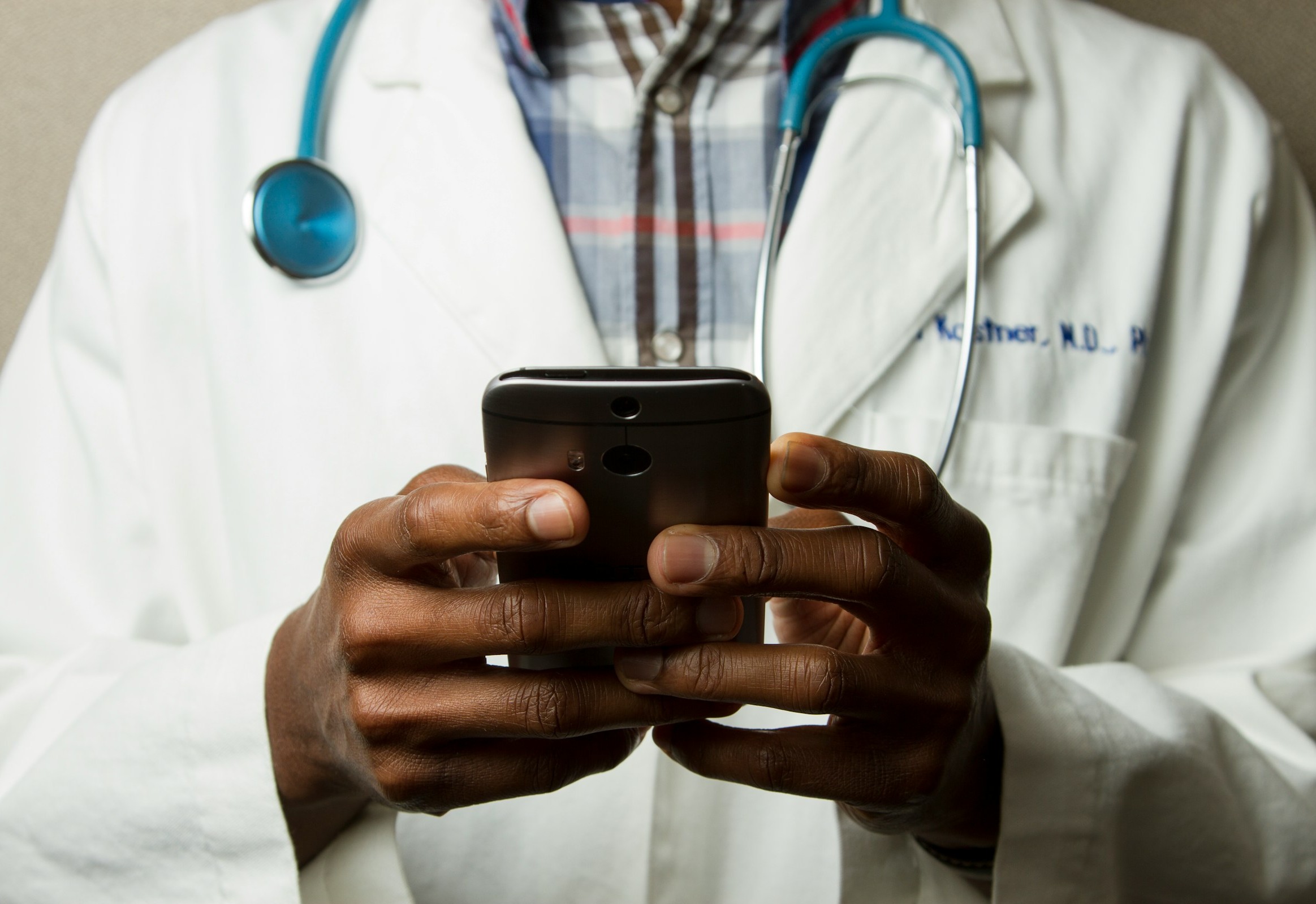 Doctor on a smartphone illustrating the AI Airlock scheme from the Medicines and Healthcare products Regulatory Agency (MHRA) in the UK that aims to accelerate the adoption of artificial intelligence technologies into the NHS healthcare system with a high emphasis on safety.